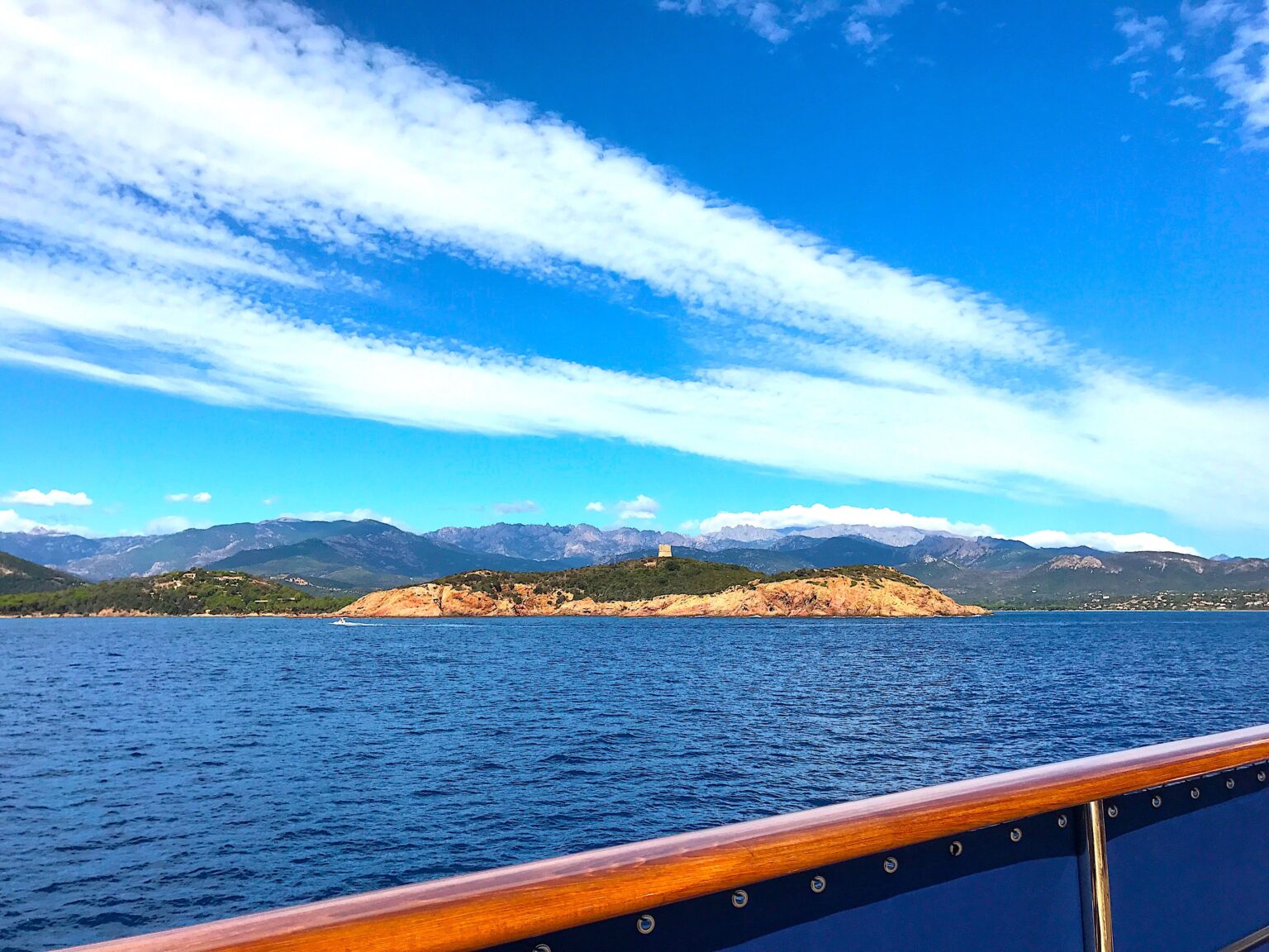 Bateau de croisière avec vue sur la mer et une île, ciel bleu
