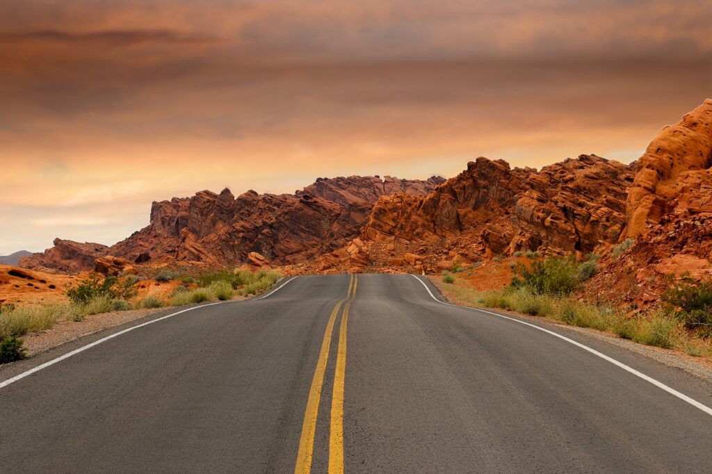 Route dans l'Ouest américain avec un coucher de soleil, rochers et environnement aride, Etats Unis